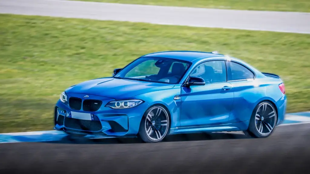 Voiture sportive bleue roulant sur un circuit automobile.